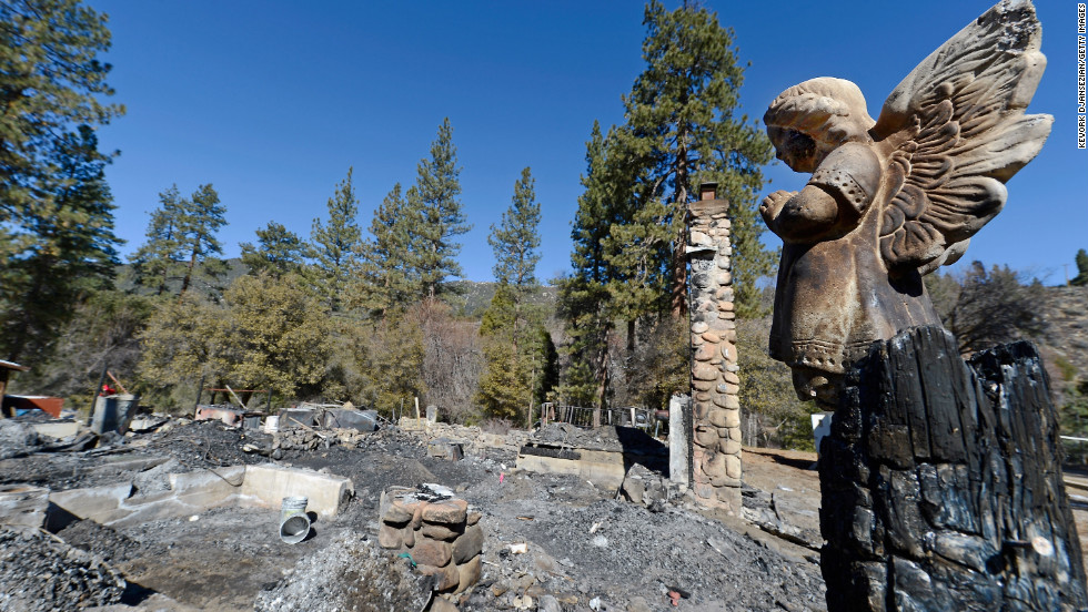 A statue of an angel stands on a wood column in front of the burned cabin on February 15.