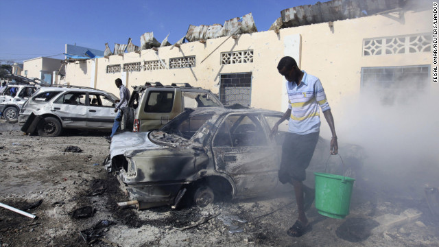 A man carries a bucket of water at the scene of an explosion in Mogadishu, Somalia, on Saturday, February 16.
