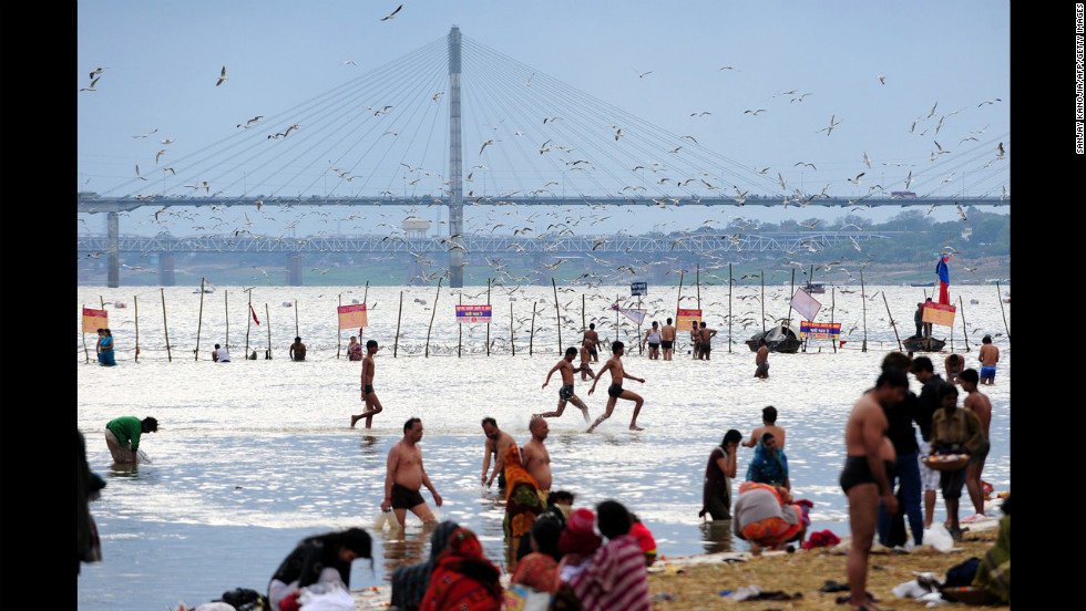 Young men run in the waters of the Sangam as Hindu devotees bathe on Saturday, February 16.