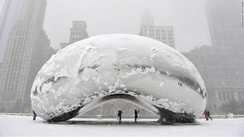 People stand under the snow-covered &quot;Cloud Gate&quot; sculpture, commonly known as &quot;the bean,&quot; on Tuesday, March 5, in Chicago, Illinois.