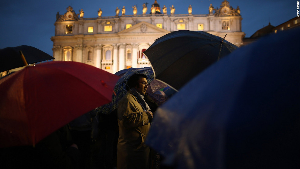 People shield themselves from the rain in St. Peter&#39;s Square after the election of the new pope.
