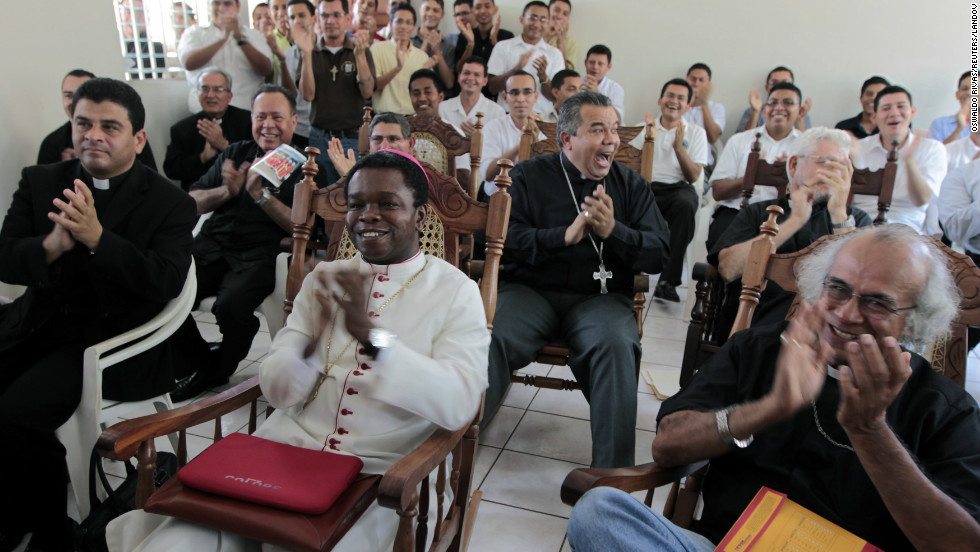 Fortunatus Nwachukwu, in white, the Vatican&#39;s ambassador to Nicaragua, applauds as he watches a local television station announcing the new pope with others in Managua, Nicaragua.