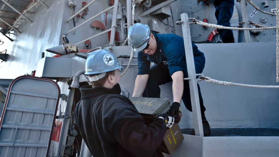 Fire Controlman 2nd Class Jason Titcombe, left, hands Fire Controlman 2nd Class Joshua Clements ordnance aboard the destroyer USS Lassen in this Navy handout photo taken on March 5.