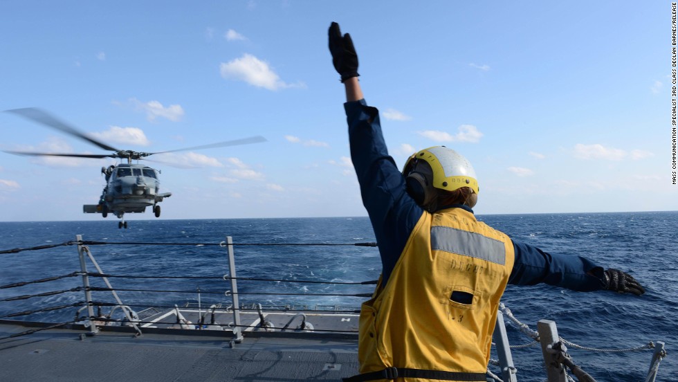 U.S. Navy Boatswain&#39;s Mate 3rd Class Brittany Chiles signals to an SH-60B Seahawk helicopter as it lands on the flight deck of the destroyer USS McCampbell on March 4 in the Pacific Ocean, in this Navy handout photo.