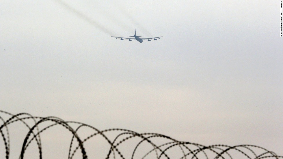 A B-52 bomber flies over the wire-topped fence of a U.S. air base in Osan, South Korea, on Tuesday, March 19.