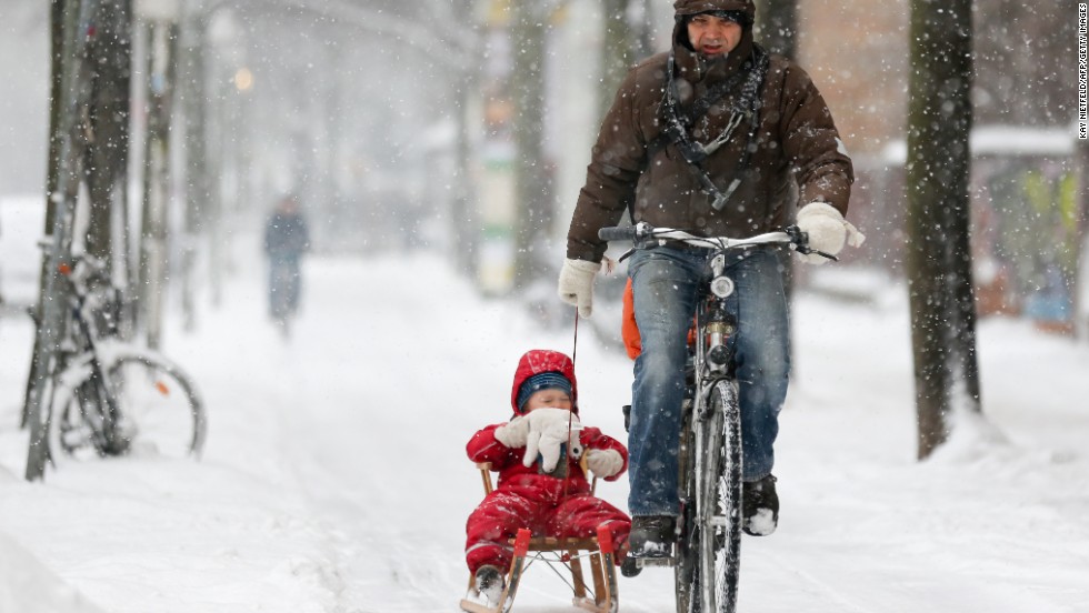A bicyclist pulls a child on a sled through the snow on Thursday, March 21, in Berlin.