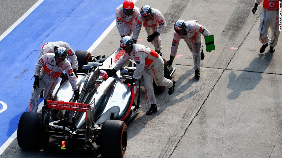 Jenson Button&#39;s car is pushed back to the pit area after his crew let the McLaren leave with a loose front wheel. It ruined the 2009 world champion&#39;s chances of earning points and he retired before the end of the race. However, his new Mexican teammate Sergio Perez finished ninth.