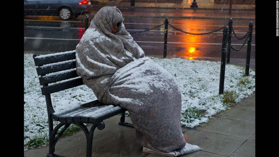 Snow collects on a man sleeping on a bench early Monday, March 25, in Washington, D.C.