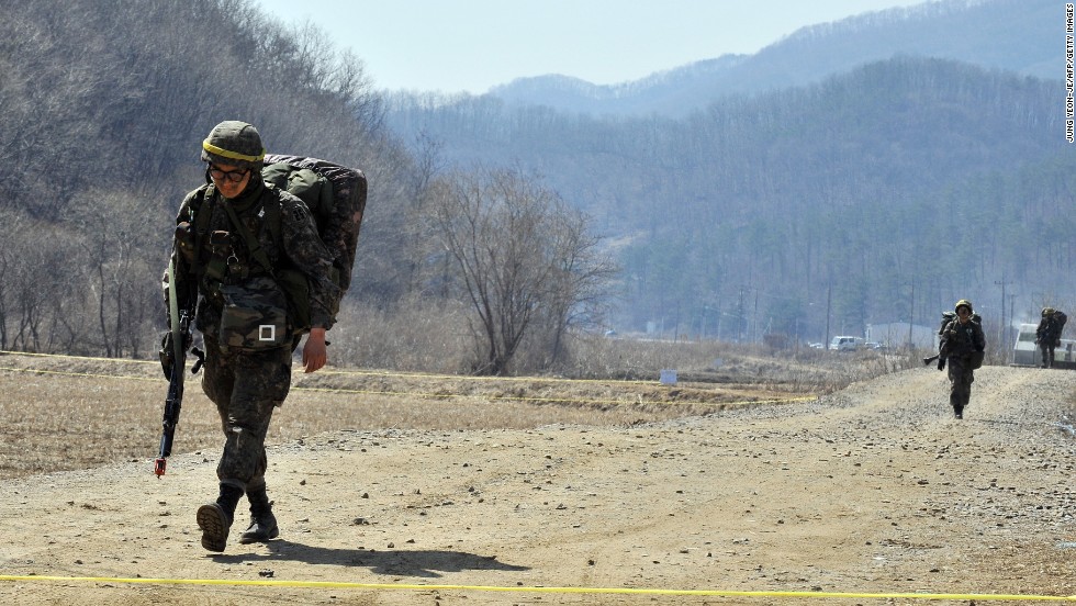 Armed South Korean soldiers walk on a road near a military drill field in Paju on March 27.