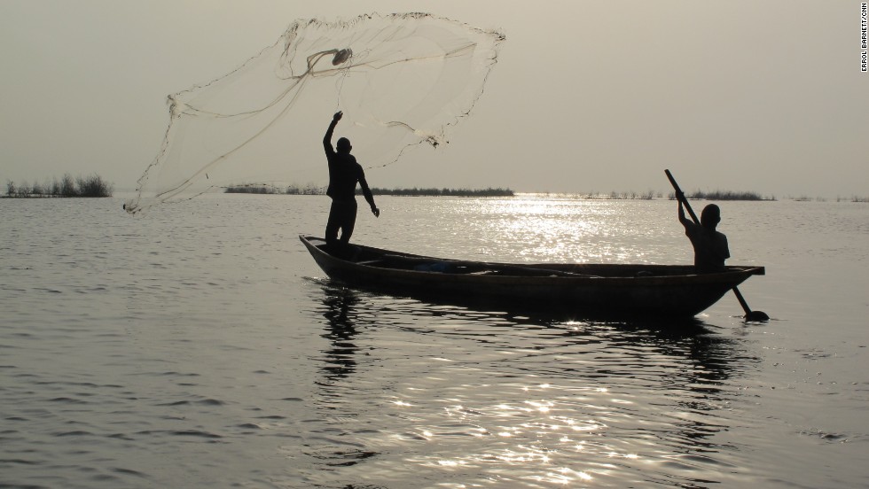 A fisherman throws out his net on the lagoon&#39;s calm waters. Fisherman immigrating from Benin and Togo initially settled Makoko over a century ago. But as the population of Lagos exploded to its current size of at least 15 million, so too did the population of Makoko. Estimates are anywhere from 85,000 to 250,000 people live there.