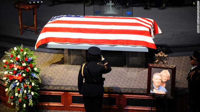 An officer salutes the casket during a memorial service for District Attorney Mike McLelland and his wife, Cynthia, on Thursday in Sunnyvale, Texas.