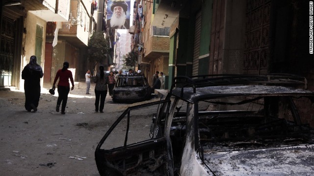 A portrait of a past Coptic pope hangs above a burnt-out car after clashes between Christians and Muslims in Khosous, Egypt.