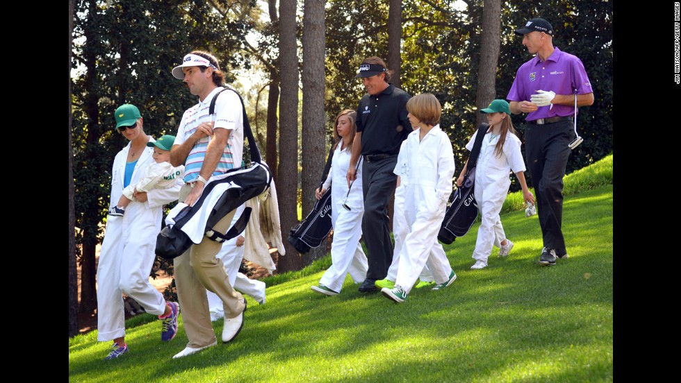 Bubba Watson, left, walks with his wife Angie and son Caleb, followed by Phil Mickelson, center, with kids Evan, Amanda, and Sophia and Jim Furyk, right, with daughter Caleigh.