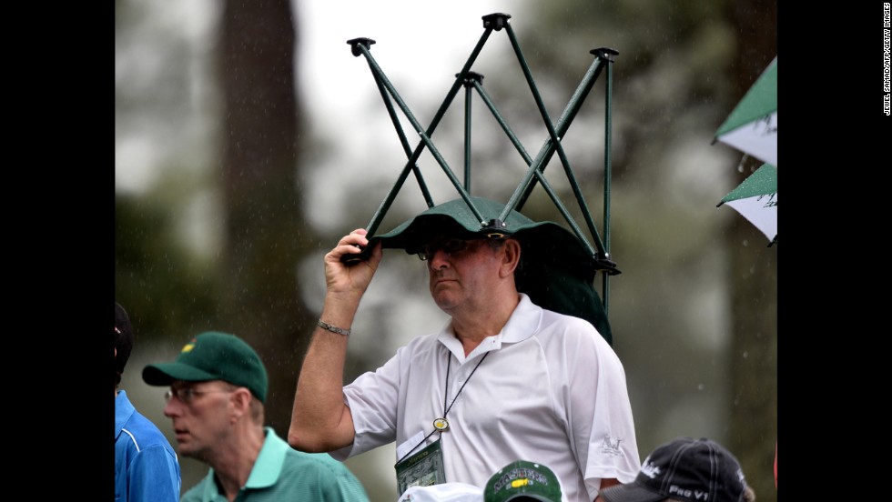 A fan takes cover in the rain during the second round on April 12.