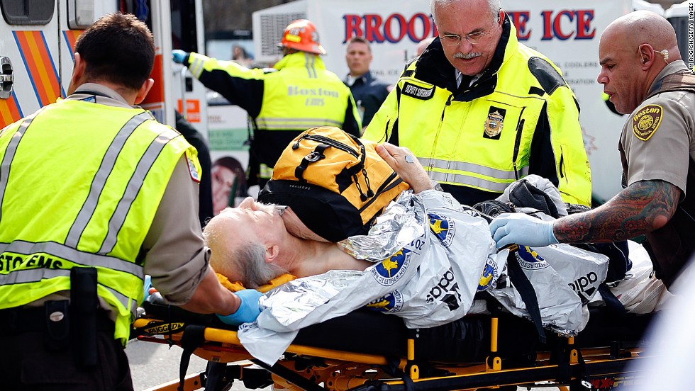 An injured man is prepared to be moved from a stretcher to an ambulance.