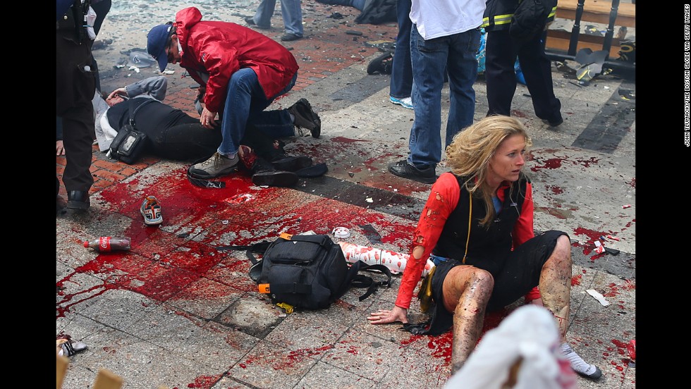 Victims lie on the ground at the scene of the first explosion.