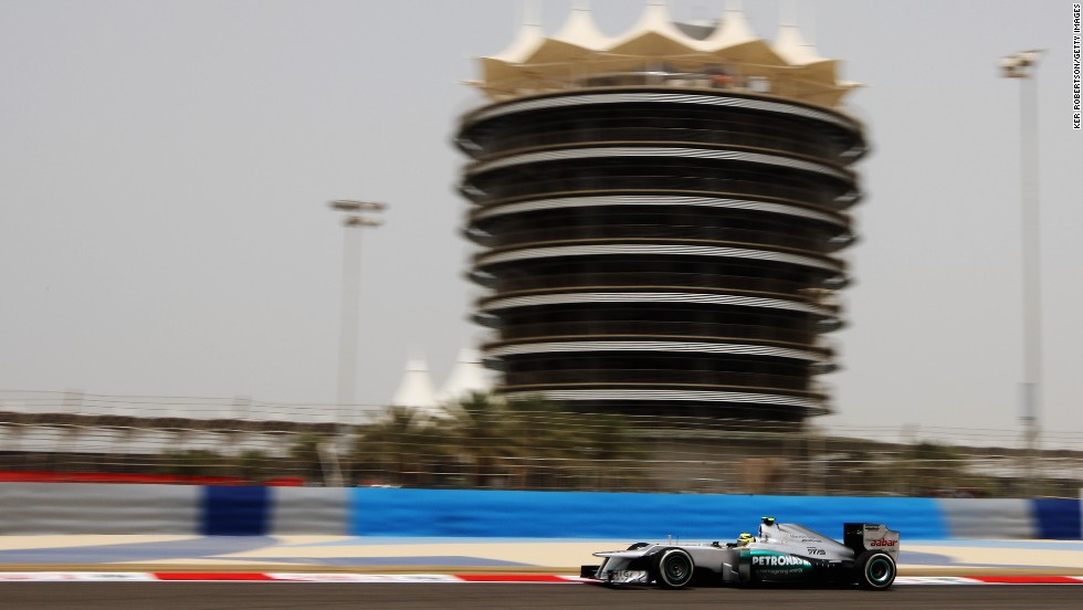 The imposing Sakhir Tower looms over the cars as they race on the Bahrain International Circuit.