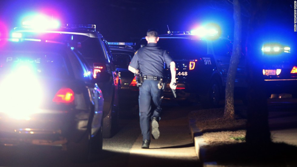 A police officer runs with his gun drawn on Friday.