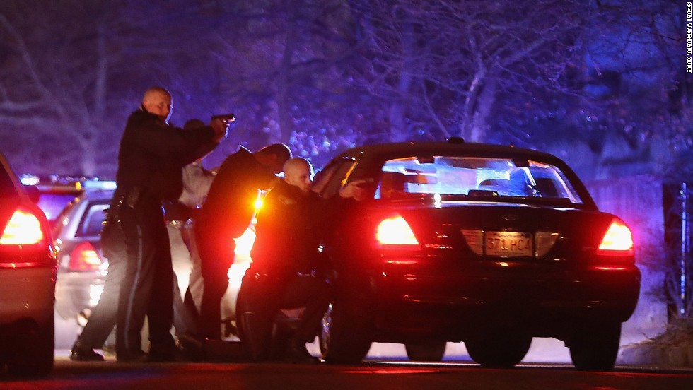 Police with guns drawn search for a suspect on Friday in Watertown, Massachusetts.