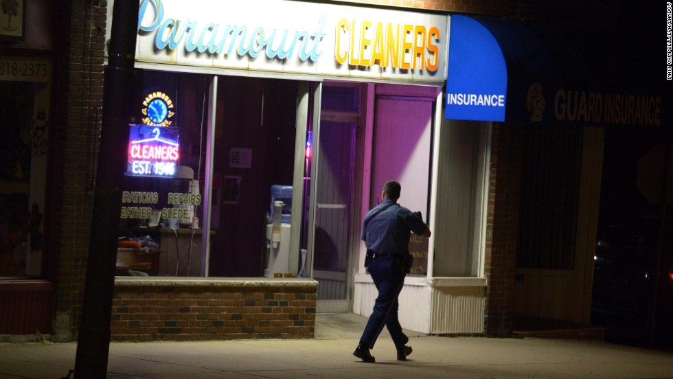 A Massachusetts state trooper checks a building along Mount Auburn Street as police search neighborhoods in Watertown.