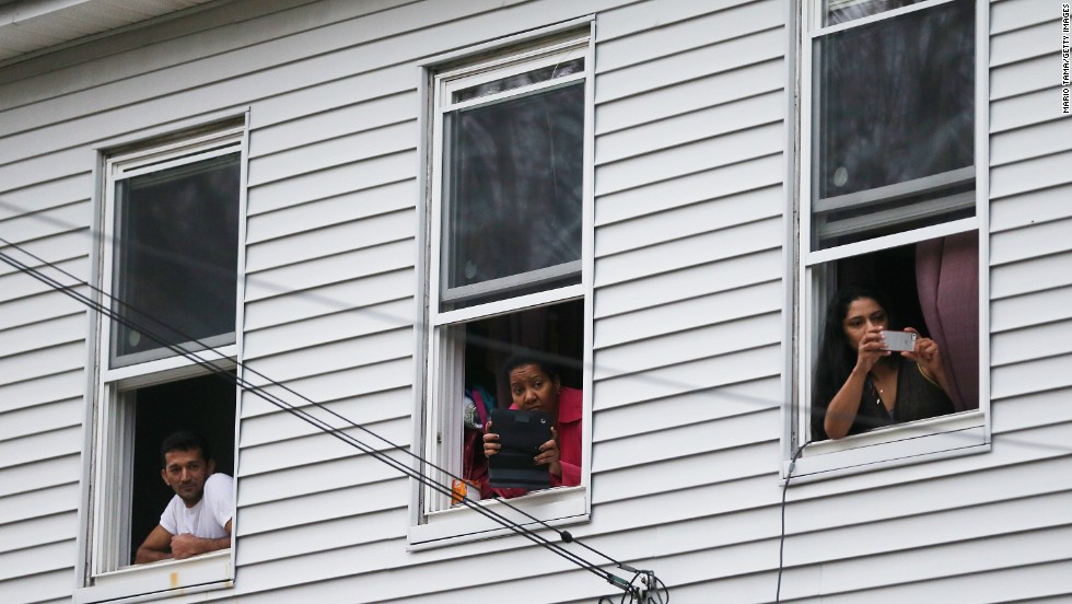 Onlookers take pictures while SWAT team members look around on Friday.