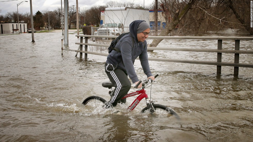 Hector Duran uses his bike to get through floodwater on Friday, April 19, in Des Plaines, Illinois. The suburban Chicago town is battling rising floodwater from the Des Plaines River.