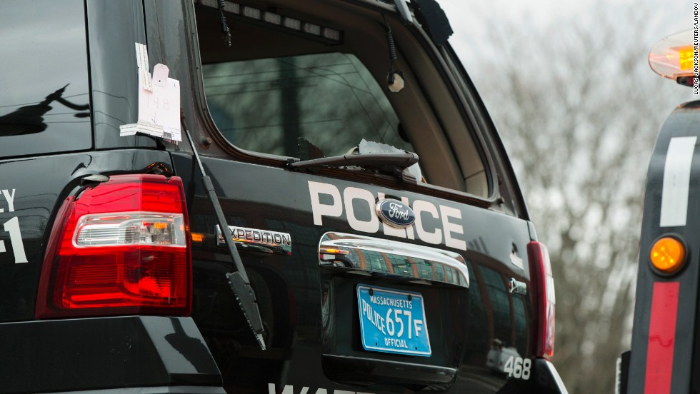 A Watertown police vehicle with bullet holes in its body and a shattered windshield is towed out of the search area on April 19 in Watertown, Massachusetts.