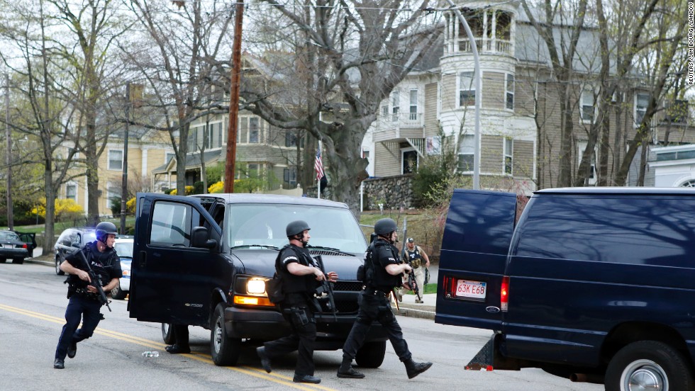 SWAT team members run toward a police assault on a house as gunfire erupts on April 19.