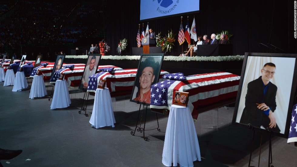 Photos of the fallen firefighters stand next to their coffins at the memorial on April 25.