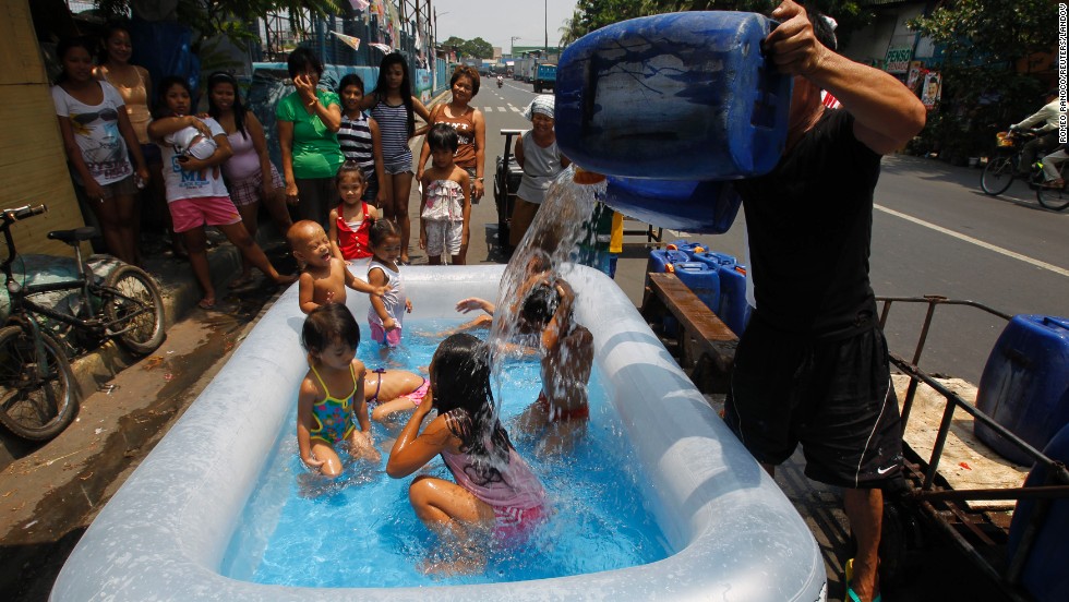A man pours water over children swimming in an inflatable swimming pool to beat the heat in Manila, Philippines, on Friday, April 26.