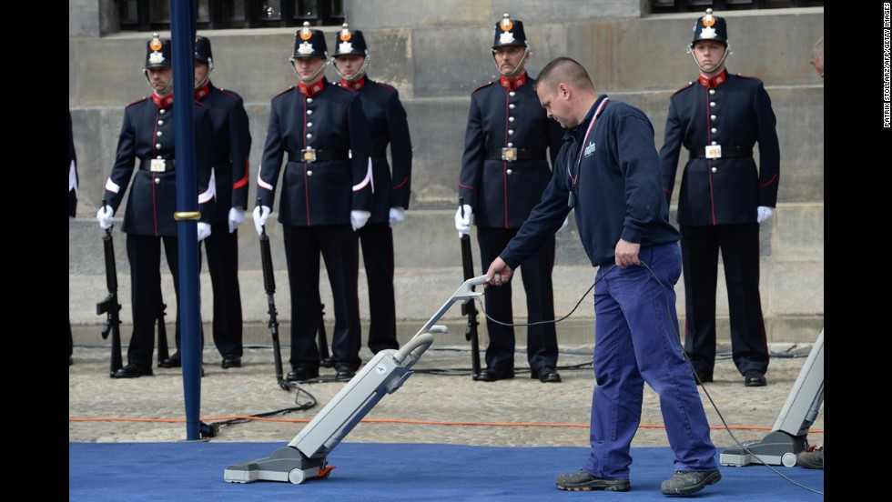 A cleaner vacuums the carpet outside the Royal Palace during Queen Beatrix&#39;s abdication ceremony.
