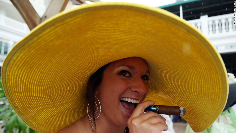 A fan&#39;s wide-brimmed hat protects her cigar from the rain.