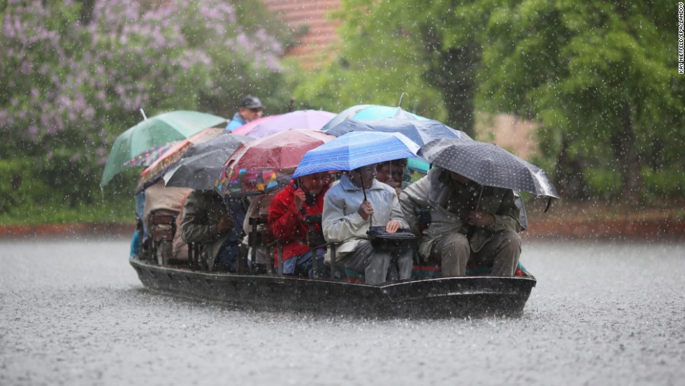 People take shelter under umbrellas during a boat ride in heavy rain on the Spreewald Canals near Luebbenau, Germany, on Sunday, May 12.