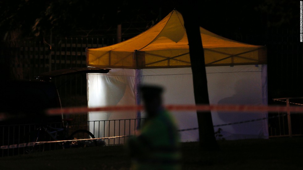 A police officer guards a tent that&#39;s been set up at the crime scene as investigations continue late May 22.