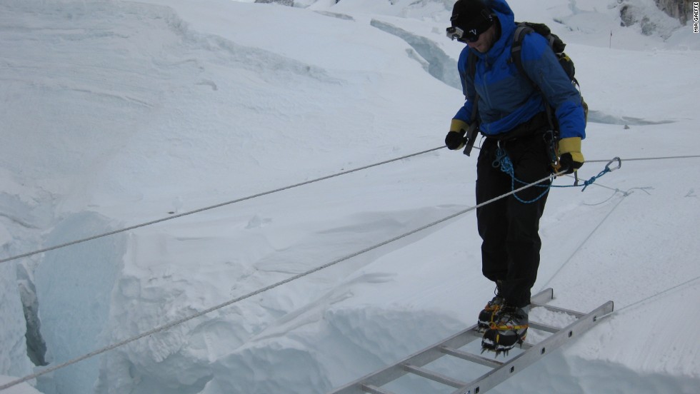 Kedrowski crosses a crevasse in the Khumbu Icefall on a ladder. Teaching clients how to walk in crampons and using other equipment in icy conditions is key to helping them acclimate.