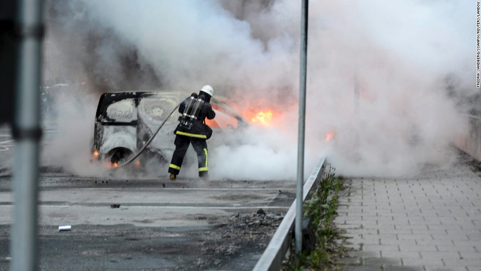 Firemen extinguish a burning car in Rinkeby outside of Stockholm on May 23.