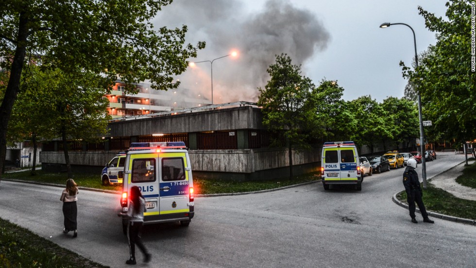Police officers secure an apartment building after overnight riots in Husby on Monday, May 20. The building had to be evacuated after a fire spread inside the parking garage.
