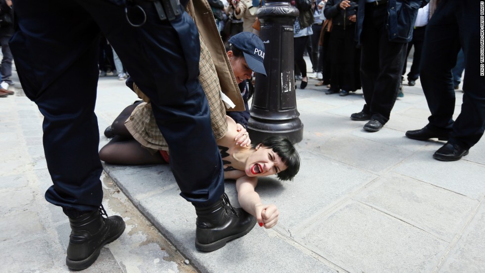 A member of the FEMEN feminist activist group with writing on her chest reading &quot;May fascists rest in hell&quot; is arrested by police officers after taking part in a protest at Notre Dame Cathedral in Paris on Wednesday, May 22.  The protesters were demonstrating against the suicide of a far-right activist inside the cathedral the previous day.