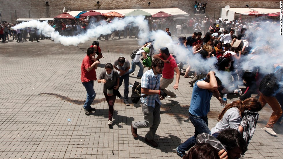 A crowd scatters during clashes on May 31, as one demonstrator throws back the tear gas canister that was launched by riot police.