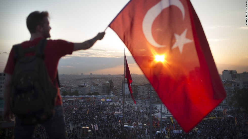 A protester waves the Turkish flag from a rooftop at Taksim Square on June 3 as large crowds continue to demonstrate below.