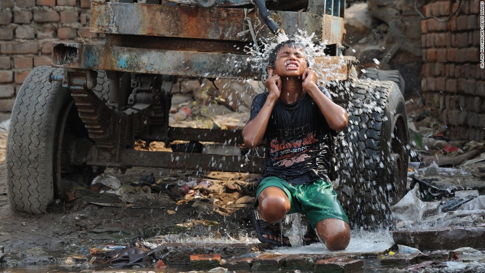A boy cools off under a water tanker in New Delhi on Tuesday, June 4.