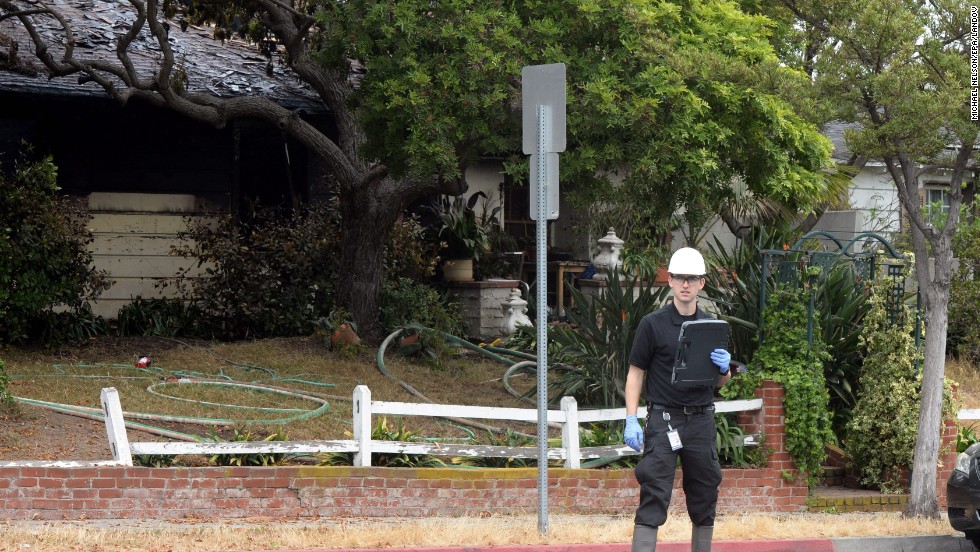 An inspector stands outside the partially burnt house where two bodies were discovered near the Santa Monica College campus.