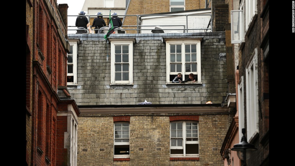 Activists look through windows as police stand guard on the rooftop on June 11.