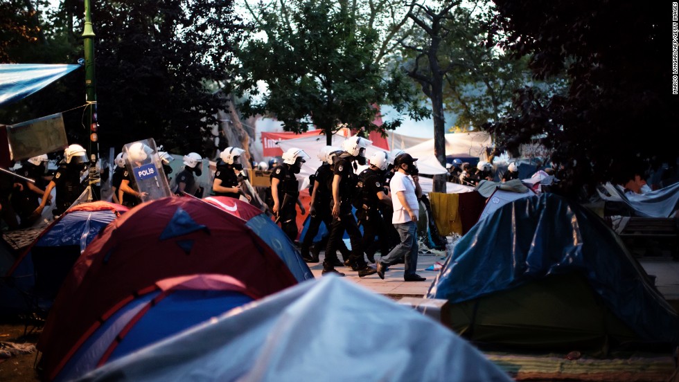 Riot police move in a line through the tent camp on June 15. 