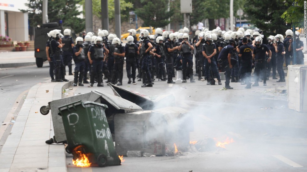 Trash containers burn in front of riot police forces in Ankara, Turkey, on June 16.