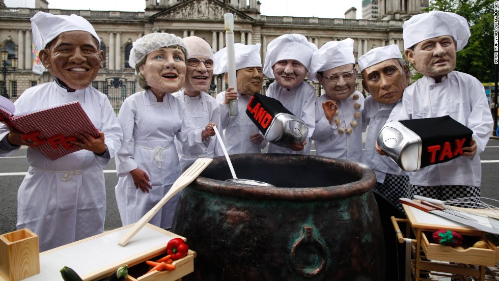 Oxfam charity volunteers wearing masks depicting the G8 leaders stand around a large cauldron outside City Hall in Belfast on June 16 to draw attention to the issue of world hunger.