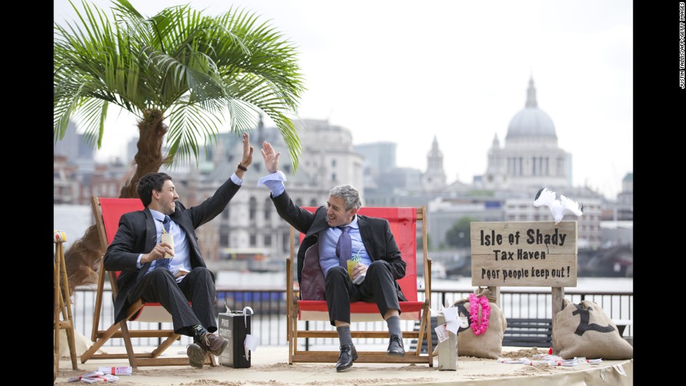 Protesters in suits high-five on the set of their &quot;Isle of Shady Tax Haven&quot; in London on Friday, June 14.