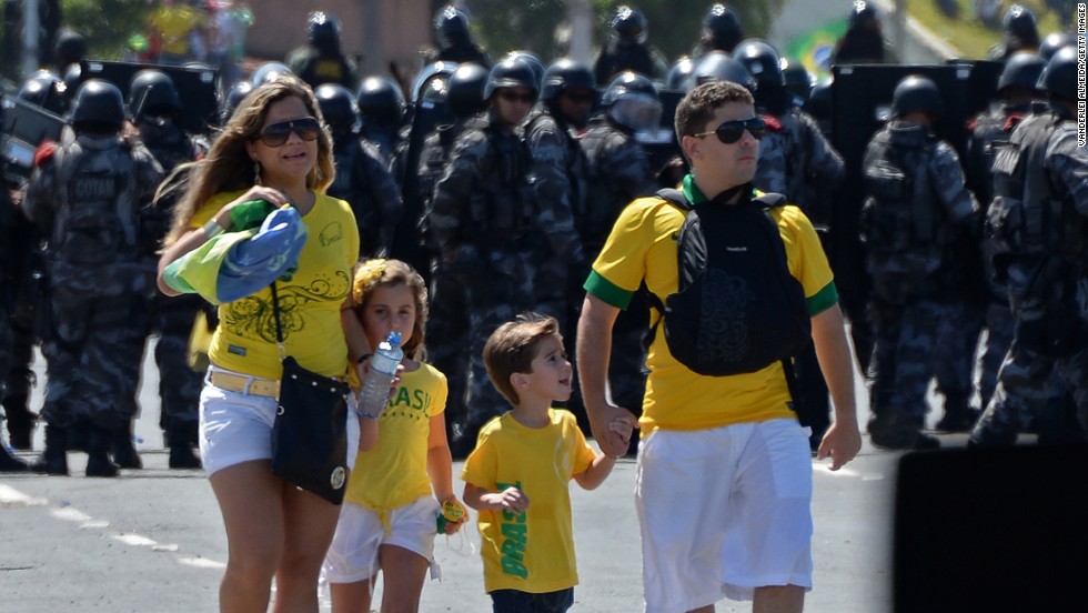 A family of four negotiate their way to the game as riot police prevent protesters from gaining access to Fortaleza&#39;s Castelao Stadium. 