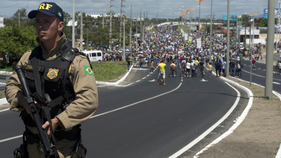 A police officer holds his weapon as protesters continue their demonstration ahead of Brazil&#39;s Group A match with Mexico in the ongoing Confederations Cup.