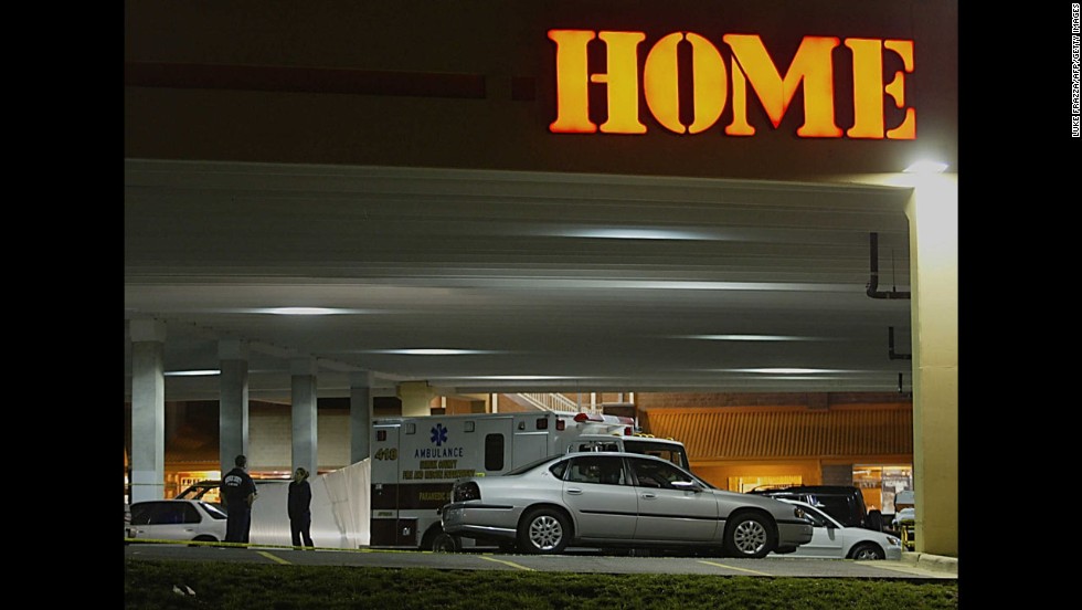 Police officers stand near the body of Linda Franklin, 47, who was shot outside a Home Depot near Falls Church, Virginia, on October 14, 2002.